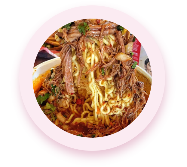 A bowl of noodles with meat and vegetables.