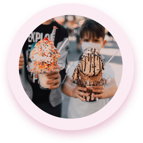 Two children holding up their hands with ice cream in them.